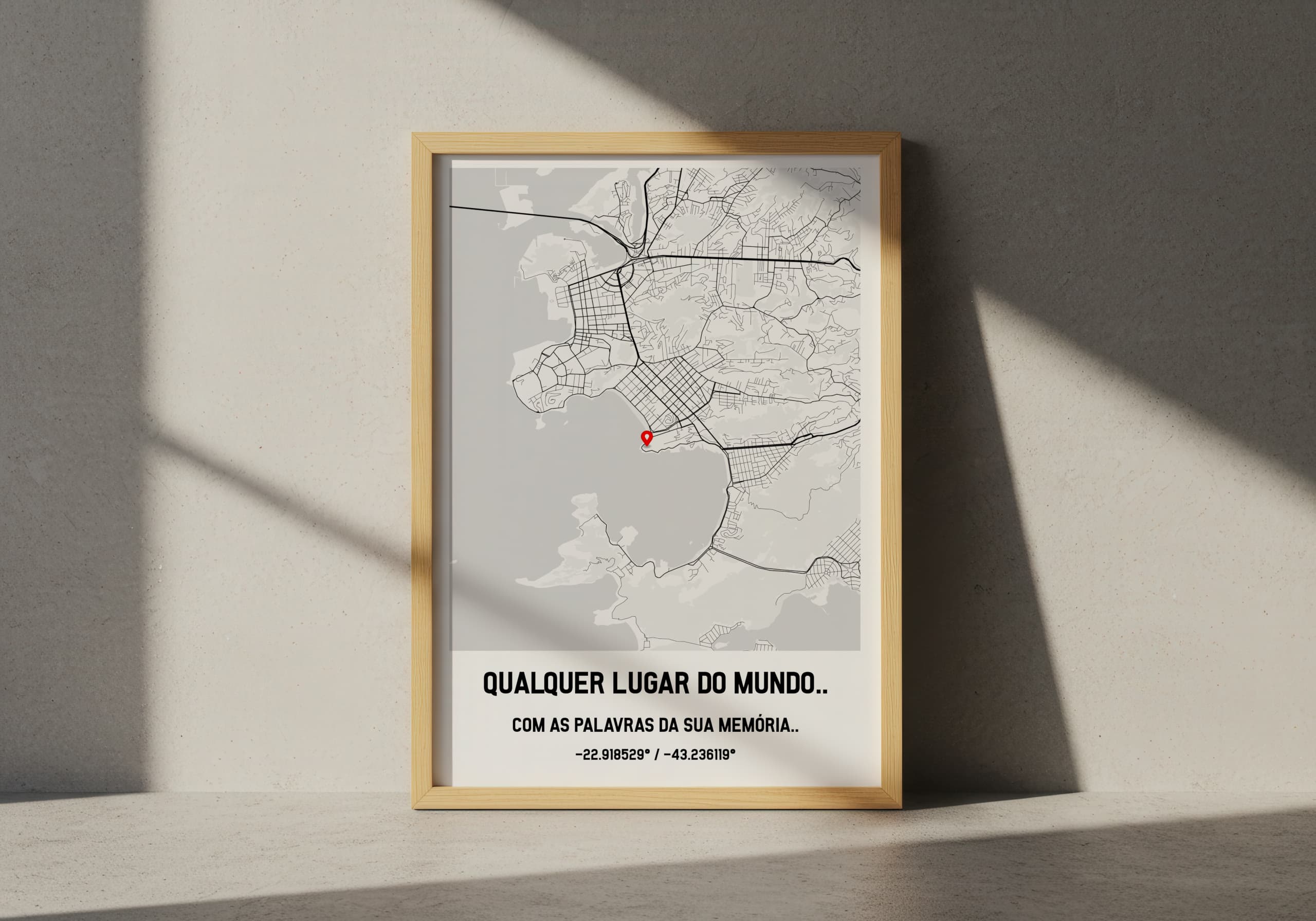 Quadro de mapa personalizado com moldura de madeira clara, apoiado no chão. O mapa exibe o texto 'Qualquer lugar do mundo...' e 'Com as palavras da sua memoria'.